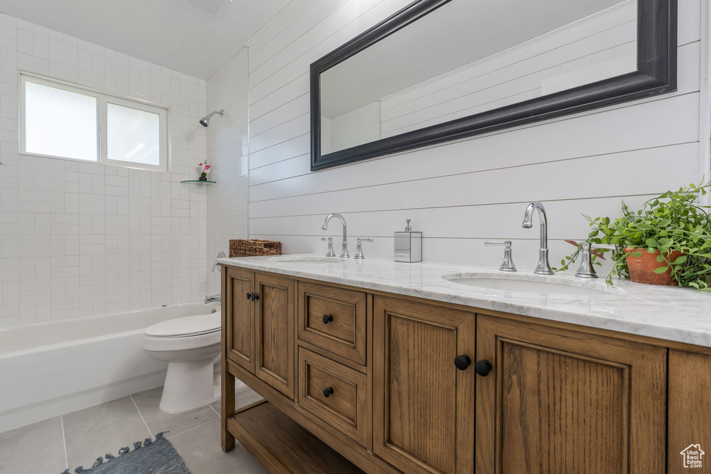 Full bathroom featuring tiled shower / bath, toilet, tile floors, and dual bowl vanity