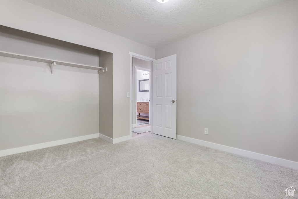 Unfurnished bedroom featuring a closet, carpet floors, and a textured ceiling