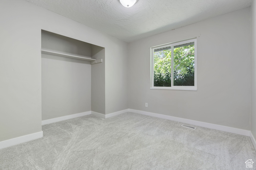 Unfurnished bedroom featuring a closet, carpet, and a textured ceiling