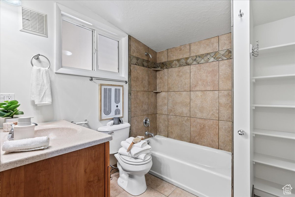 Full bathroom with vanity, tile floors, toilet, and tiled shower / bath
