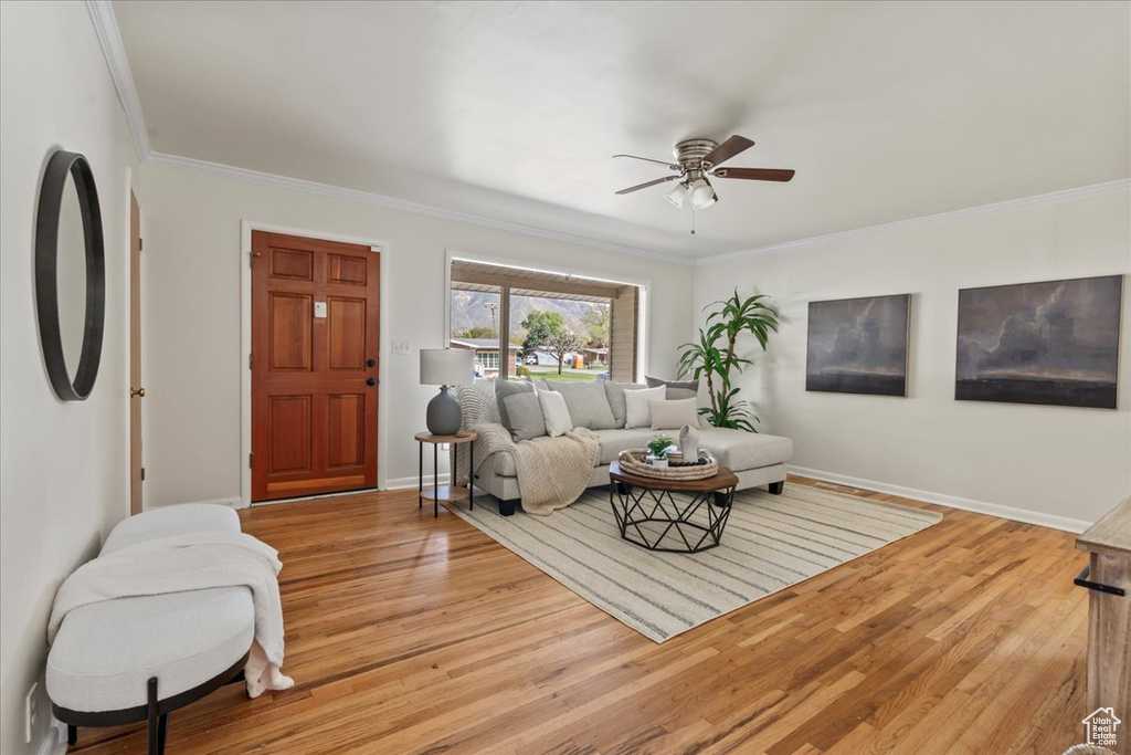 Living room with hardwood / wood-style flooring, ornamental molding, and ceiling fan