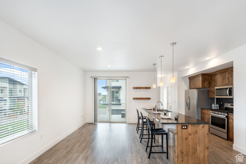 Kitchen with hardwood / wood-style floors, appliances with stainless steel finishes, and a breakfast bar