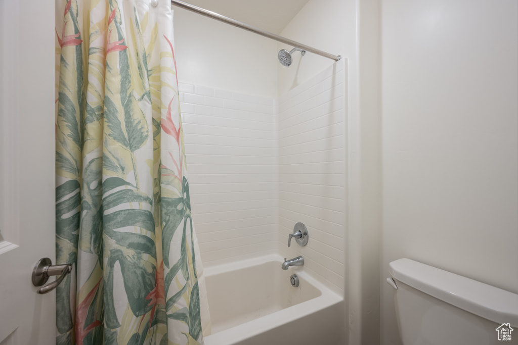 Bathroom with toilet and shower / bath combination with curtain