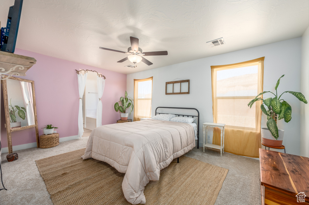 Carpeted bedroom featuring ceiling fan and ensuite bath