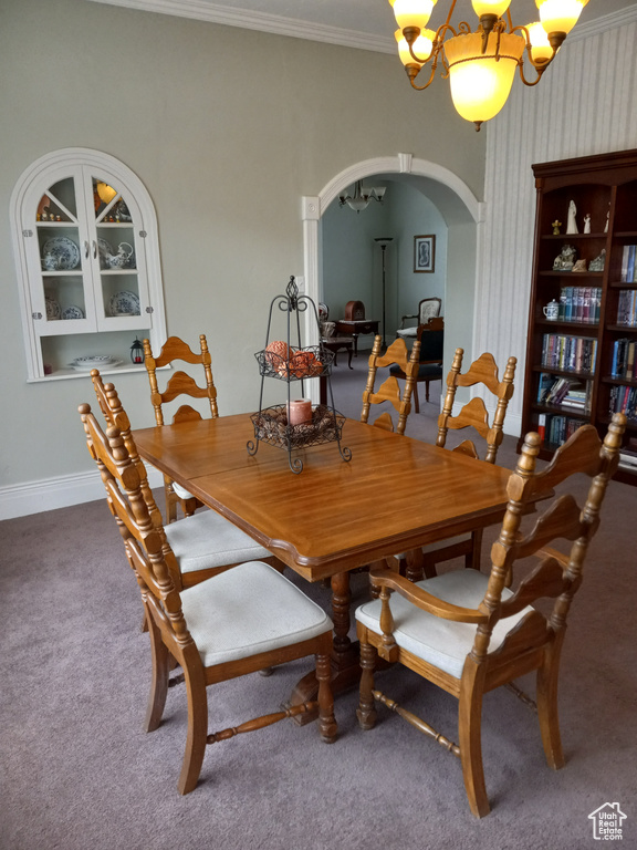 Carpeted dining space featuring crown molding and a notable chandelier