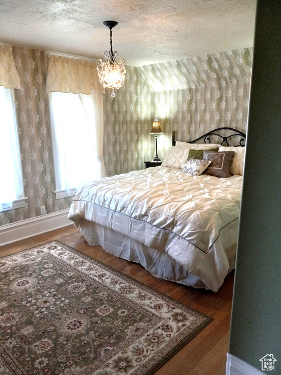 Bedroom with a chandelier, a textured ceiling, and hardwood / wood-style floors