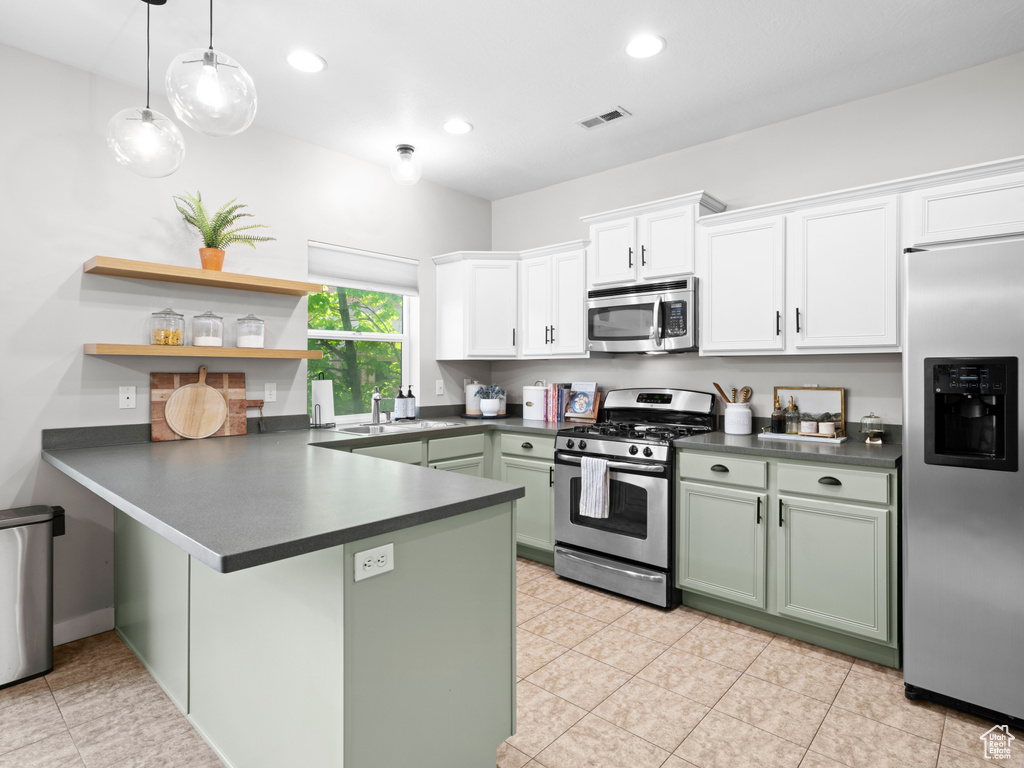 Kitchen with stainless steel appliances, light tile floors, green cabinets, and white cabinetry