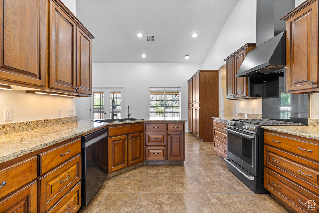 Kitchen featuring sink, dishwasher, light tile flooring, wall chimney range hood, and stainless steel range