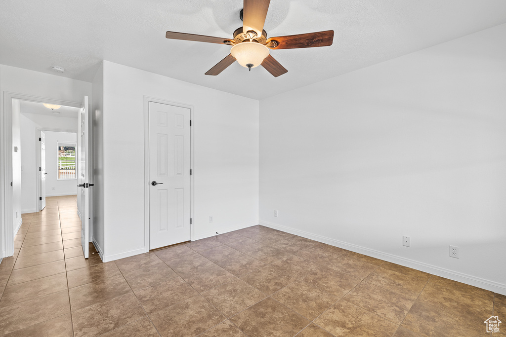 Spare room with ceiling fan and light tile flooring