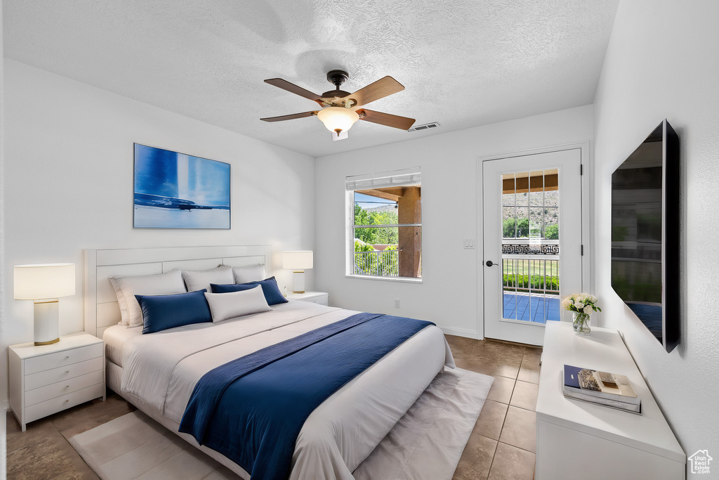 Bedroom featuring a textured ceiling, ceiling fan, access to outside, and light tile floors