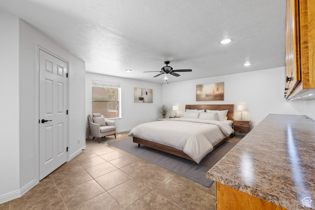 Bedroom with ceiling fan, tile floors, and a textured ceiling
