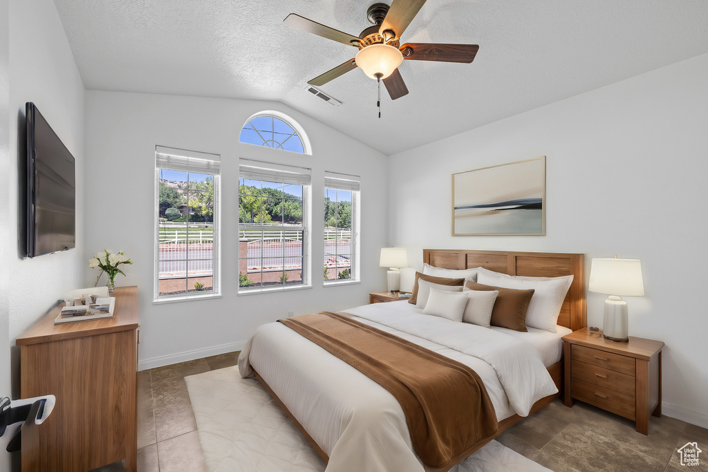 Bedroom featuring a textured ceiling, tile floors, ceiling fan, and vaulted ceiling