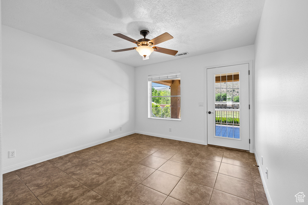 Unfurnished room featuring dark tile floors, ceiling fan, and a textured ceiling