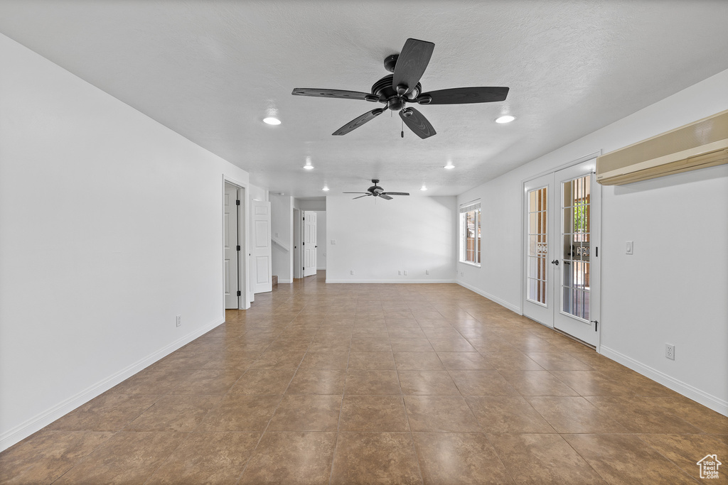 Empty room with french doors, tile floors, and ceiling fan