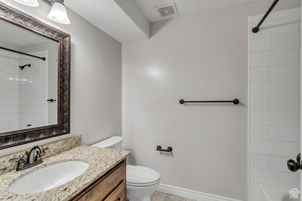 Bathroom featuring toilet, vanity, and a textured ceiling