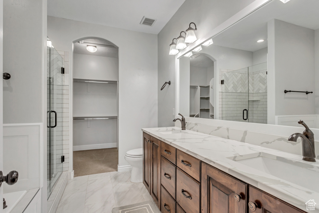 Bathroom with walk in shower, tile flooring, toilet, and double sink vanity