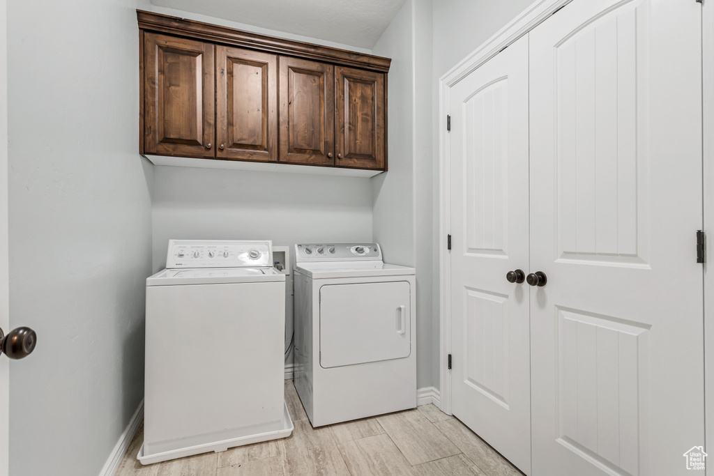 Laundry room with washing machine and dryer, cabinets, light hardwood / wood-style flooring, and hookup for a washing machine
