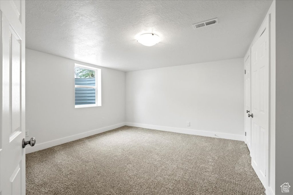 Empty room with carpet and a textured ceiling