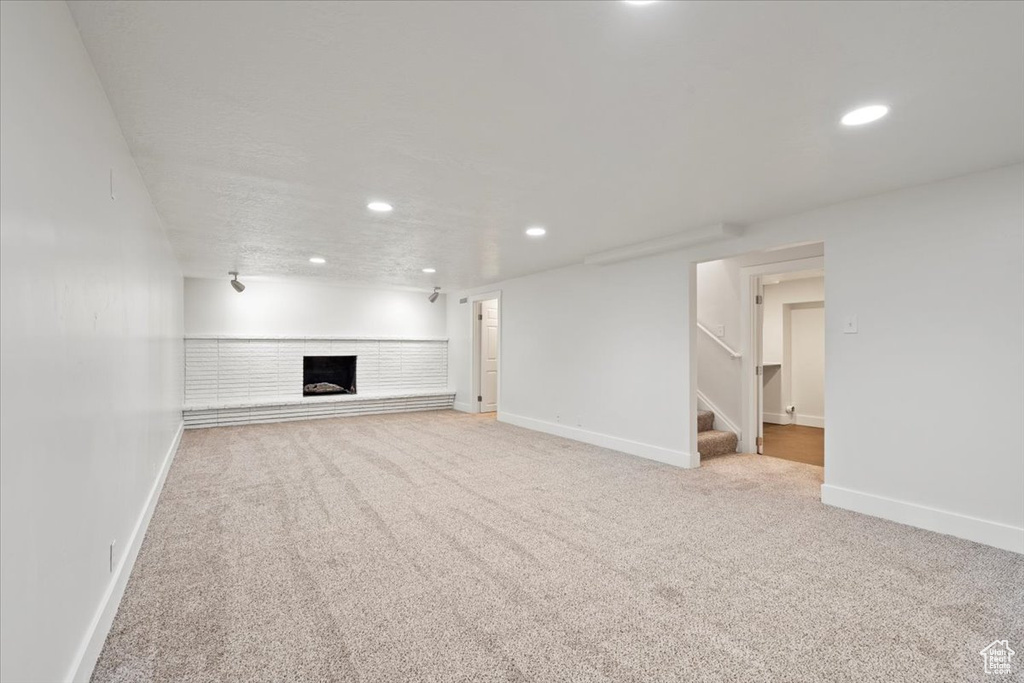Unfurnished living room featuring carpet flooring and a brick fireplace