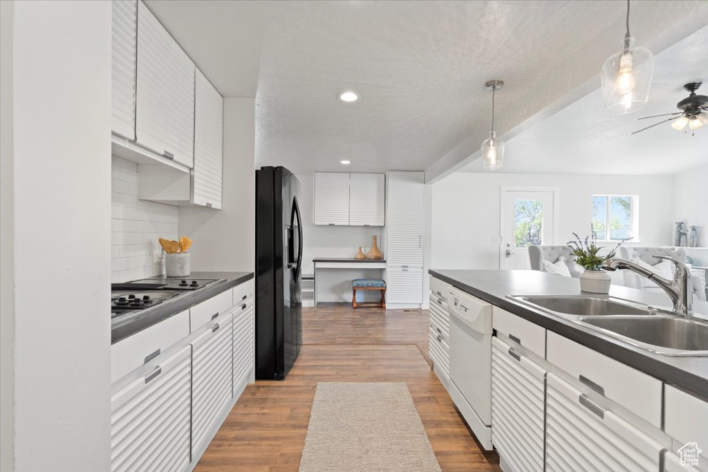 Kitchen featuring white cabinets, sink, dishwasher, light wood-type flooring, and black fridge