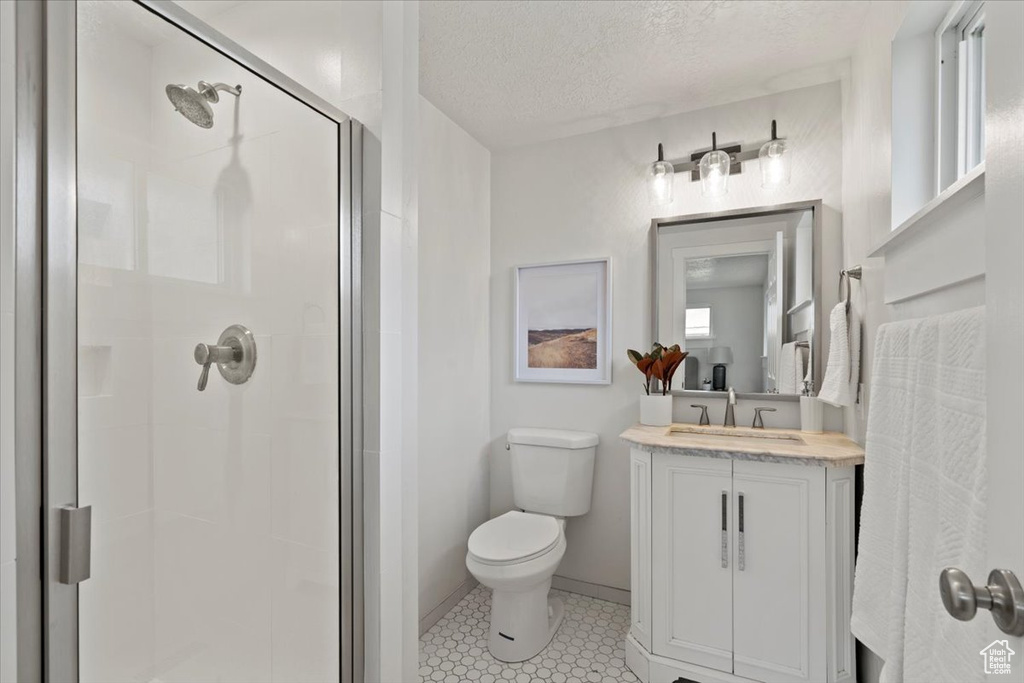 Bathroom featuring walk in shower, a healthy amount of sunlight, tile floors, vanity, and toilet
