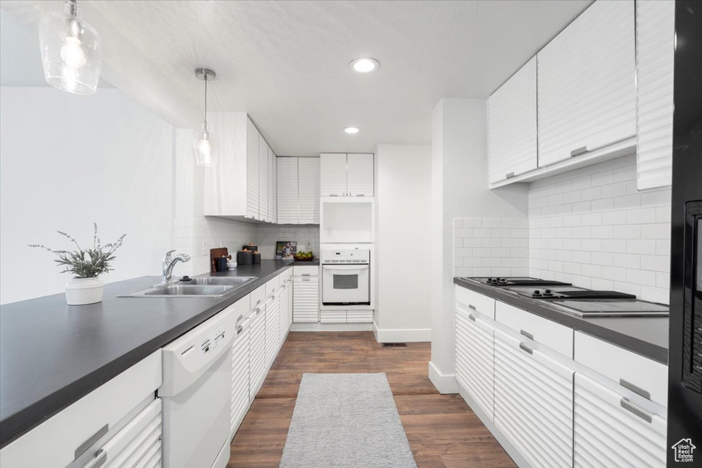 Kitchen with white cabinetry, tasteful backsplash, dark hardwood / wood-style flooring, and white appliances