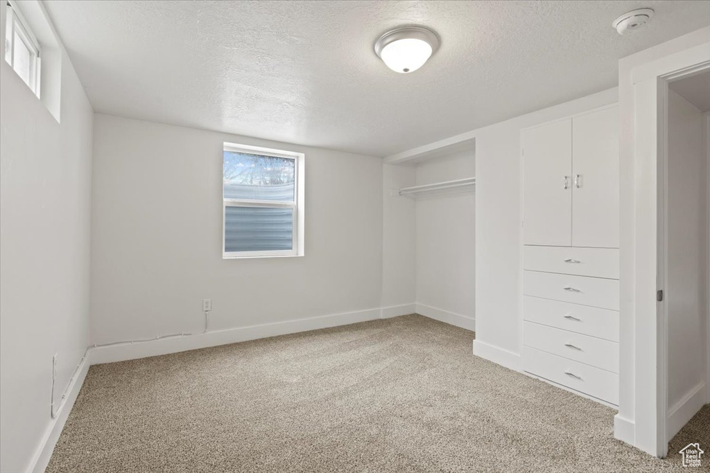 Interior space with light colored carpet, a closet, and a textured ceiling