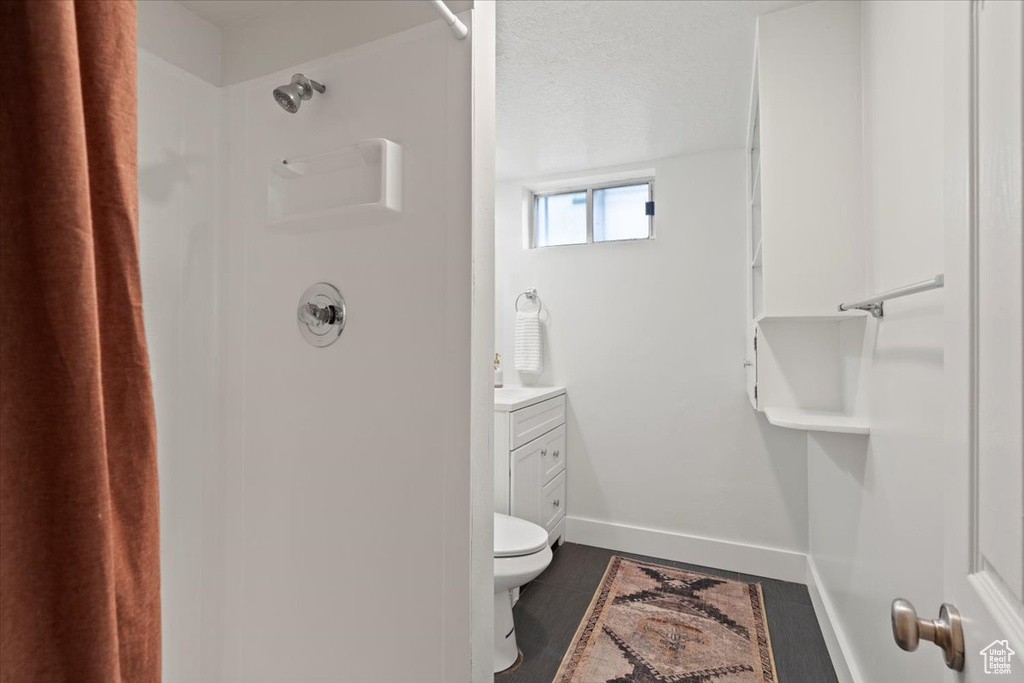 Bathroom featuring curtained shower, toilet, vanity, and hardwood / wood-style floors