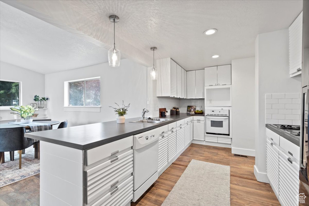 Kitchen featuring white appliances, tasteful backsplash, sink, and white cabinetry