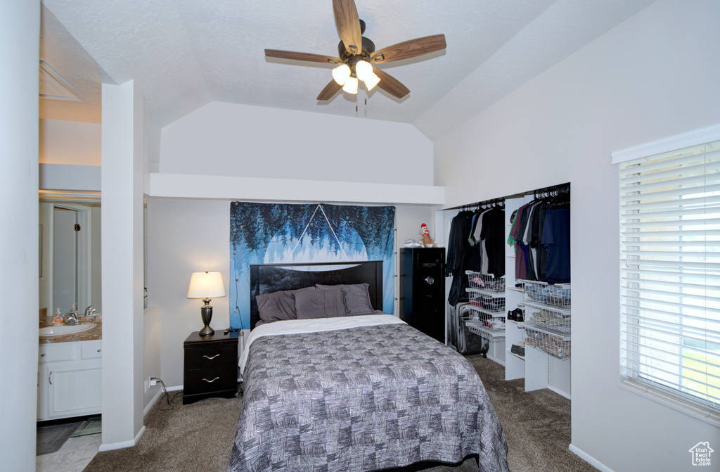 Bedroom featuring lofted ceiling, ceiling fan, ensuite bathroom, and dark colored carpet