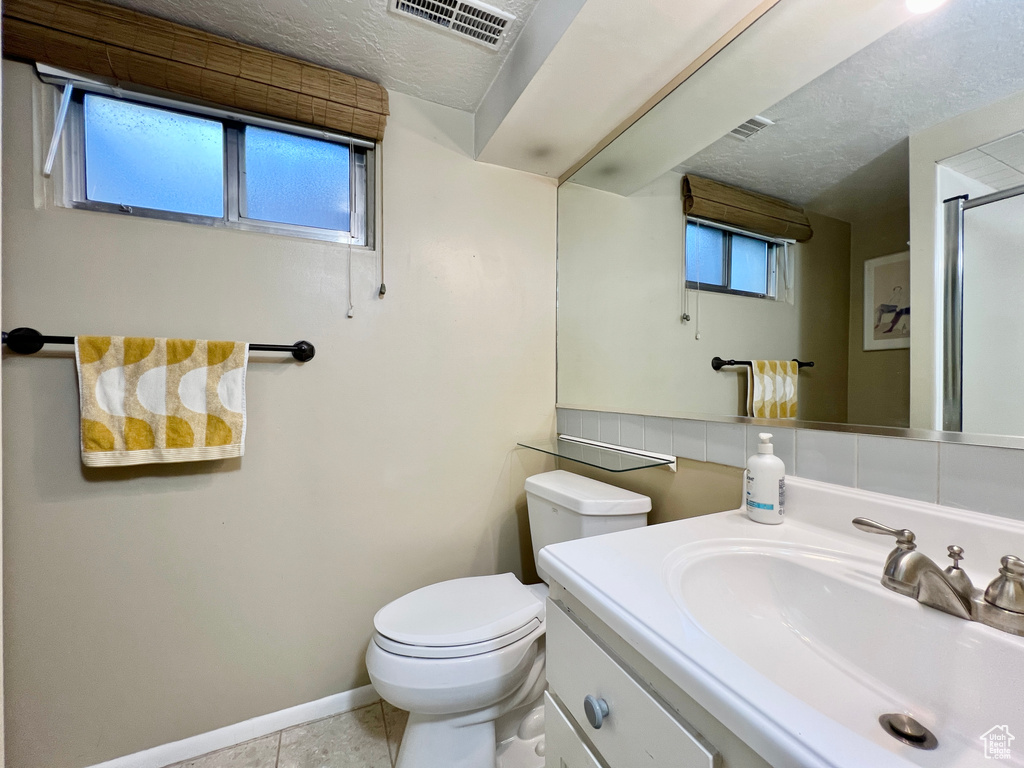 Bathroom featuring tile floors, vanity with extensive cabinet space, and toilet