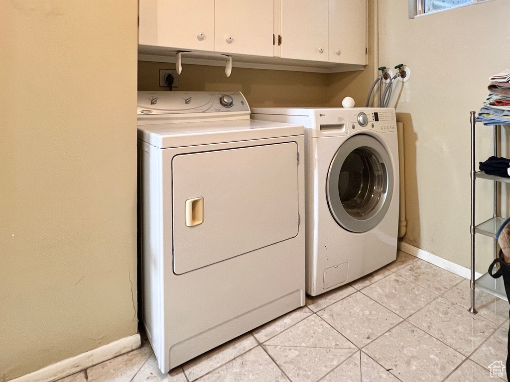 Washroom with cabinets, washer hookup, washing machine and dryer, and light tile floors