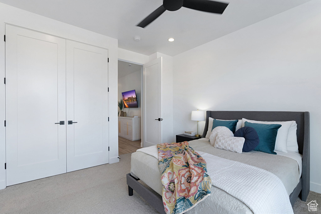 Carpeted bedroom featuring ceiling fan and a closet