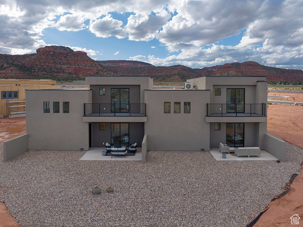 Back of house featuring a balcony, a mountain view, an outdoor hangout area, and a patio area