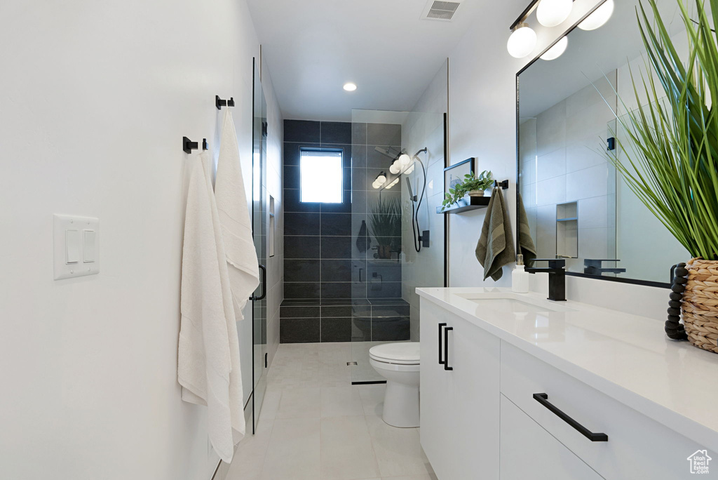 Bathroom with vanity, toilet, walk in shower, and tile patterned flooring