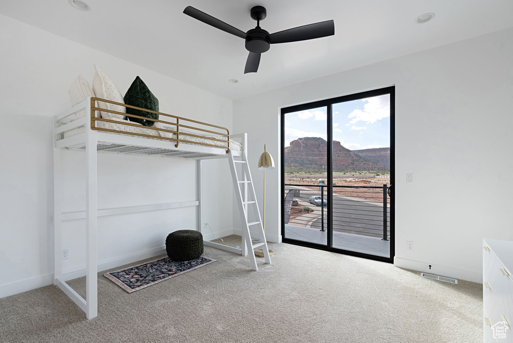 Unfurnished bedroom featuring a mountain view, access to outside, ceiling fan, and carpet