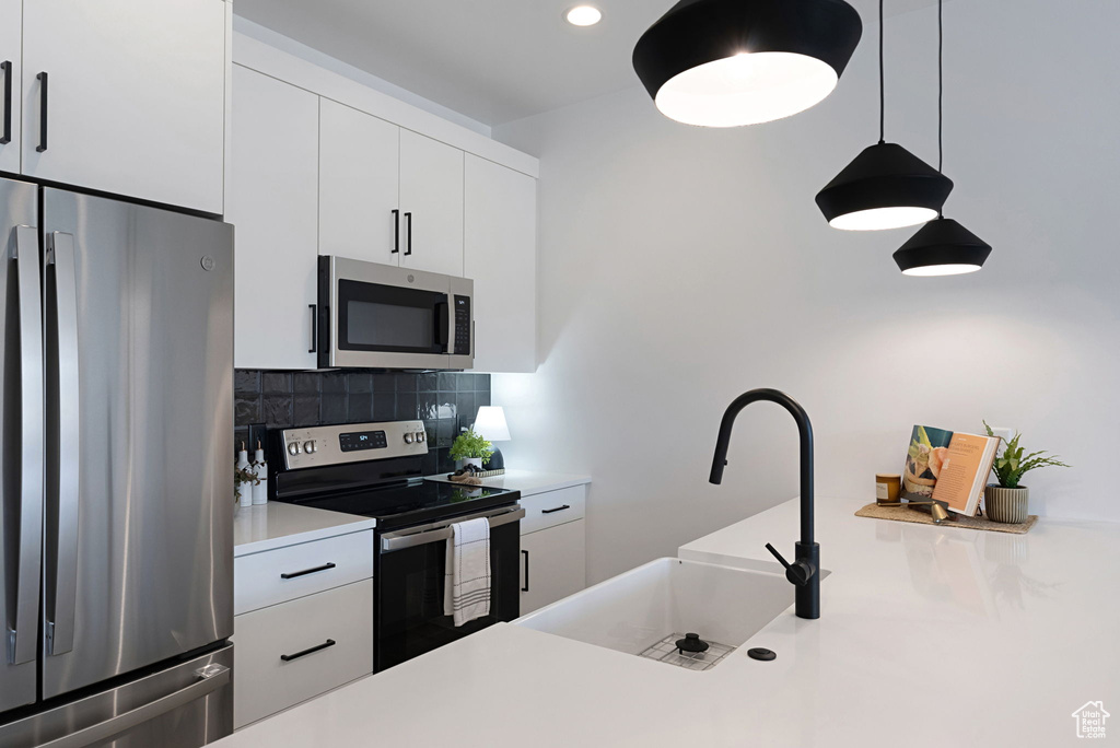 Kitchen with sink, appliances with stainless steel finishes, white cabinets, and tasteful backsplash