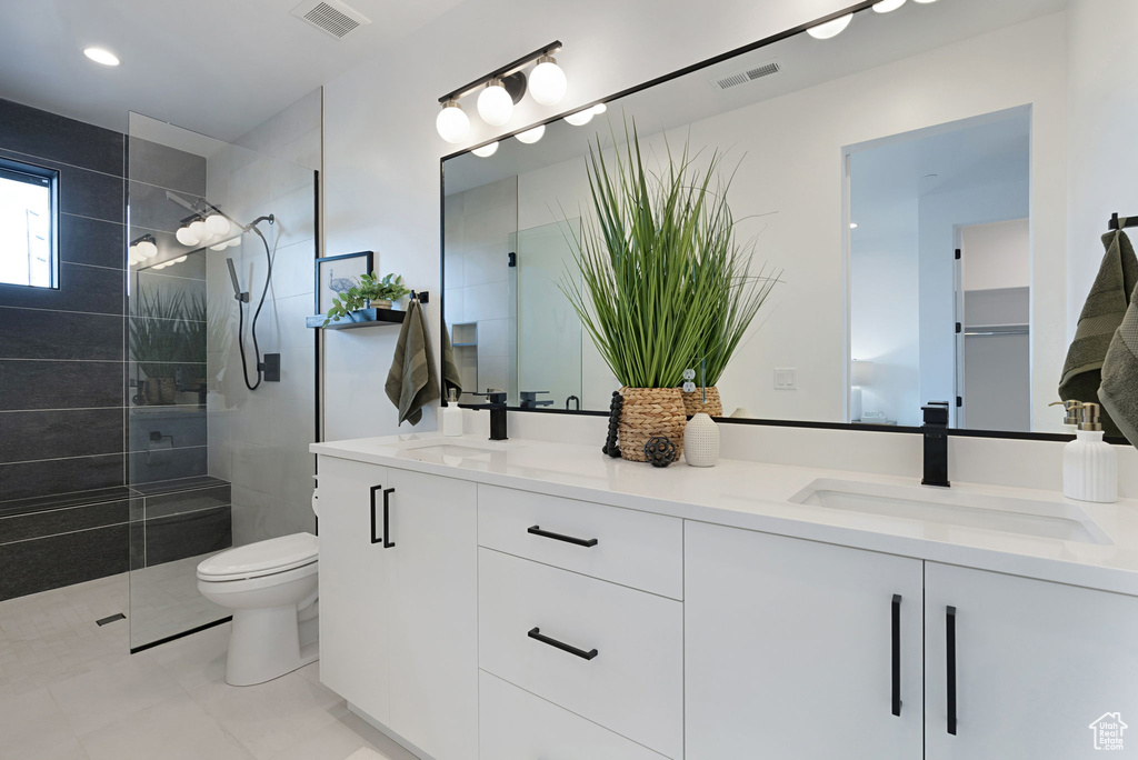 Bathroom featuring tile patterned floors, tiled shower, toilet, and vanity