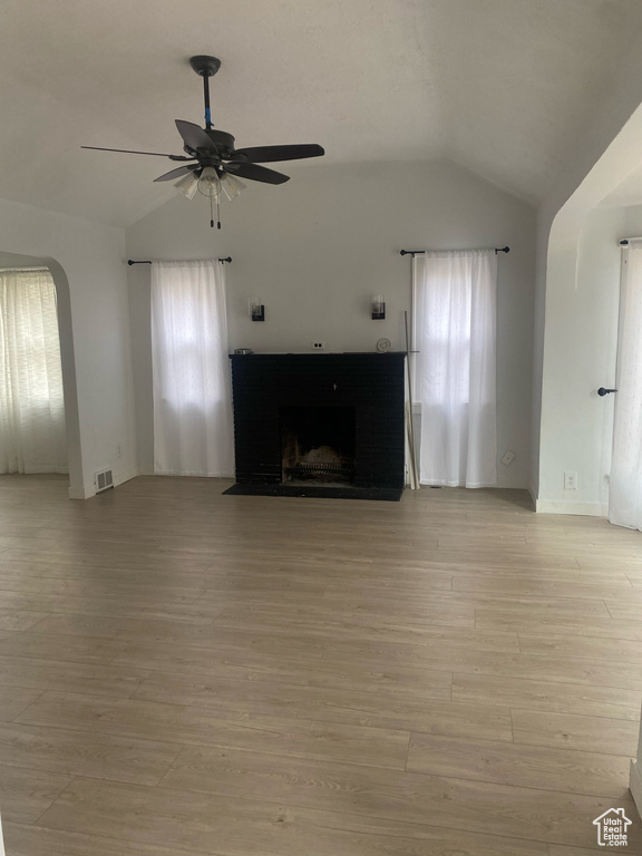 Unfurnished living room featuring lofted ceiling, plenty of natural light, ceiling fan, and light hardwood / wood-style flooring