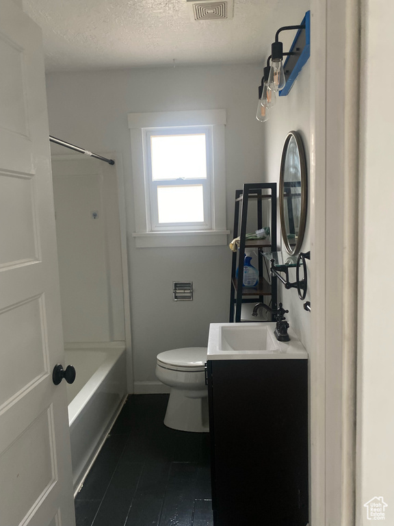 Full bathroom featuring shower / washtub combination, toilet, vanity, and a textured ceiling