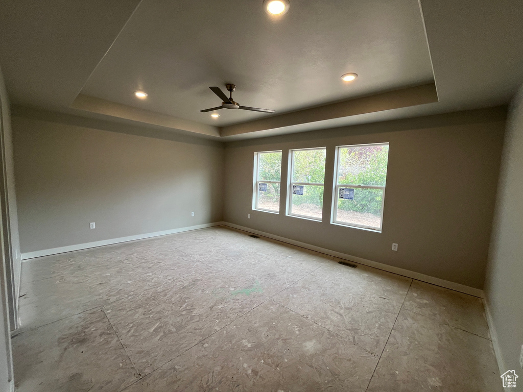 Unfurnished room with ceiling fan and a raised ceiling