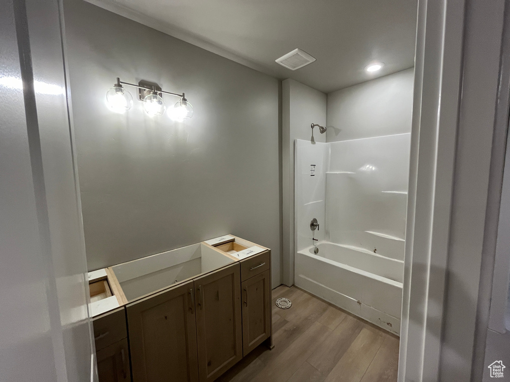 Bathroom featuring hardwood / wood-style flooring,  shower combination, and vanity