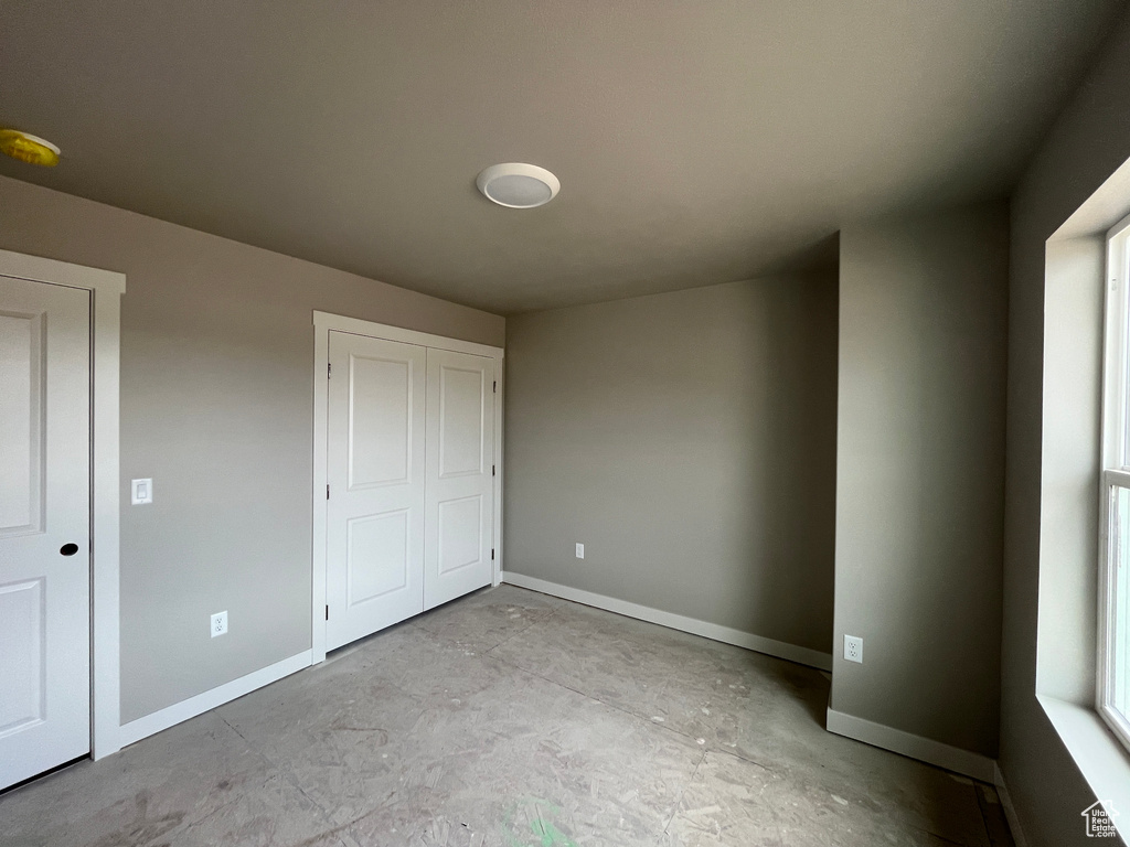 Unfurnished bedroom featuring concrete flooring and a closet