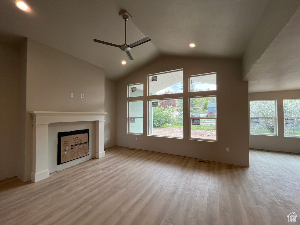 Unfurnished living room with high vaulted ceiling, light hardwood / wood-style flooring, ceiling fan, and a wealth of natural light