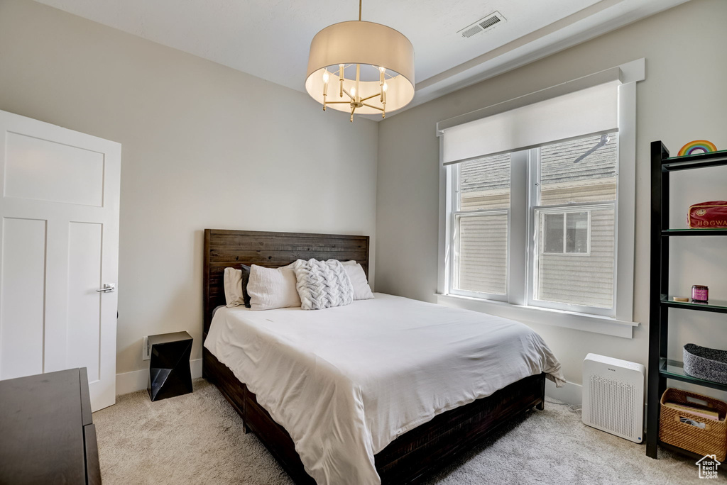 Bedroom with light carpet and a chandelier