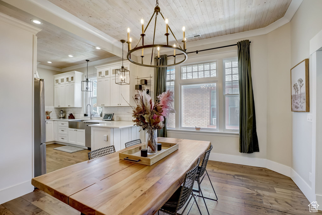 Dining space featuring sink, a chandelier, light wood-type flooring, and crown molding