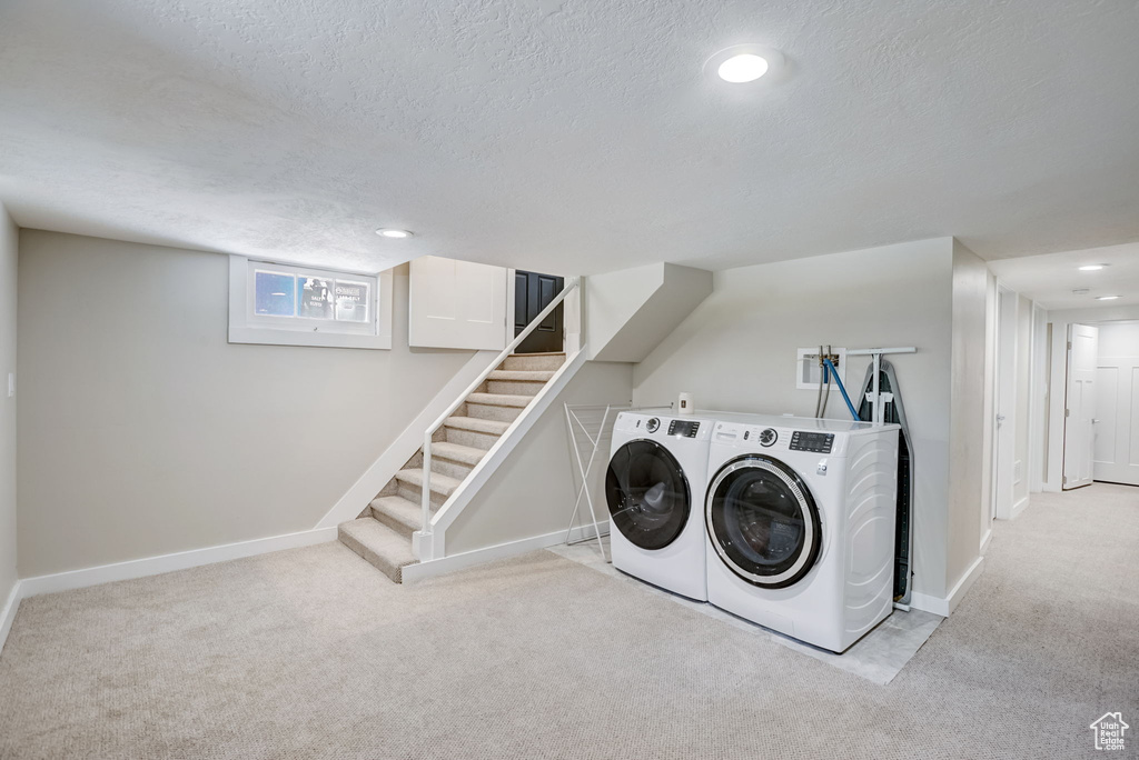 Washroom featuring washer hookup, light carpet, washing machine and dryer, and a textured ceiling