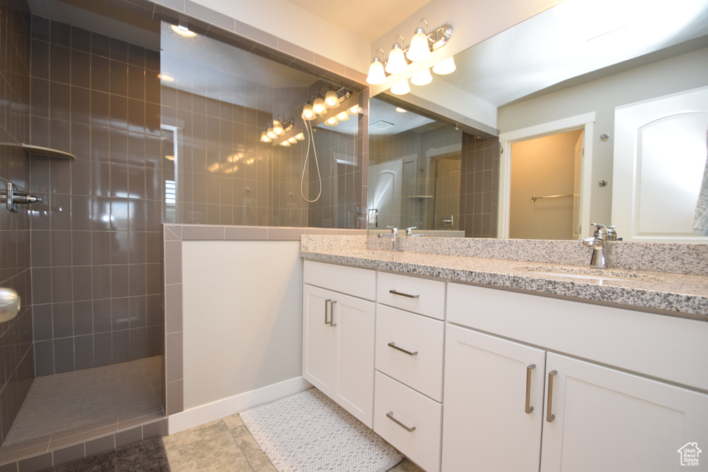 Bathroom with large vanity, tile floors, tiled shower, and double sink