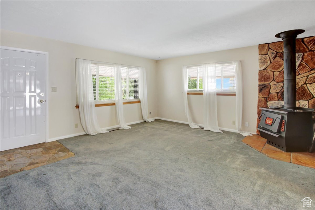 Unfurnished living room featuring a wood stove and carpet floors