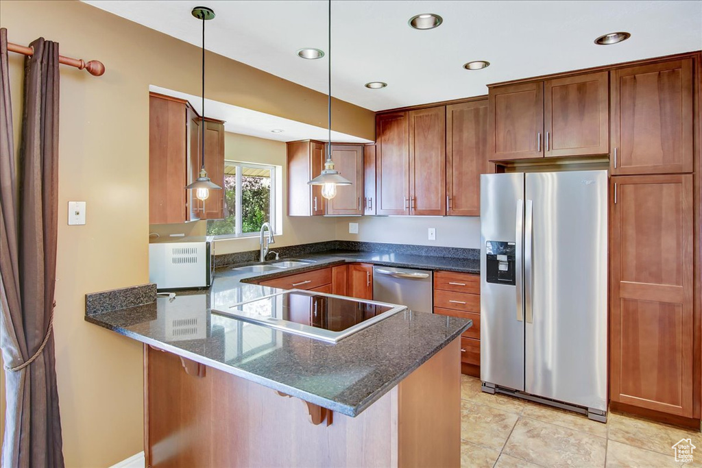 Kitchen with kitchen peninsula, appliances with stainless steel finishes, hanging light fixtures, light tile flooring, and sink